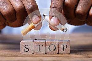 Man Breaking Cigarette Over Wooden Stop Blocks