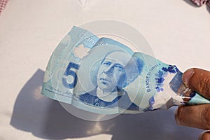 A close up of man`s hand and Canadian money- $5.00 bill