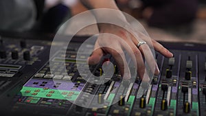 Close-up of a man's hand controls the sound, a professional mixing console in the studio, with LED backlight