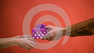 Close-up of a man`s hand that conveys a woman`s gift. Concept of celebrating new year and Christmas. Gift to Valentine`s