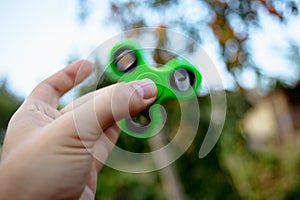 Close up of a man`s hand with green fidget spinner.