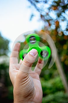 Close up of a man`s hand with green fidget spinner/.