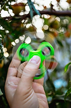 Close up of a man`s hand with green fidget spinner.