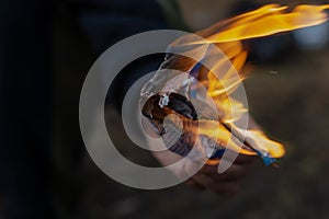 Close-up of a man`s hand holding a burning sheet of paper. Sheet