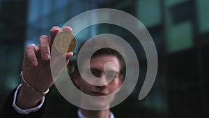 Close up of a man's hand holding a gold bitcoin coin. Rich businessman holds and shows a gold coin. Cryptocurrency