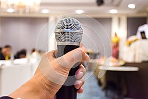 Close up of man`s hand holding microphone in conference hall