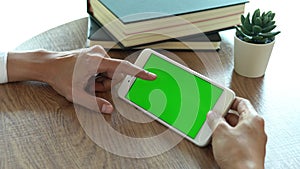 Close up of a man`s hand holding a mobile phone watching green screen, internet technology and smartphone concept
