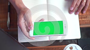 Close up of a man`s hand holding a mobile phone watching green screen, internet technology and smartphone concept