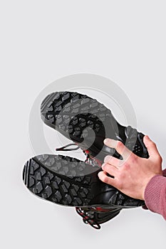 Close-up of a man`s hand holding a pair of new high black work boots made of genuine leather with a reinforced cape, the concept