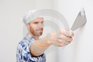 Close-up of a man`s hand holding a trowel and plastering interior wall in apartment