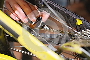 Close-up of a man`s hand, led by masters, lubricate the bicycle chain of a mountain bike with a special lubricant in the