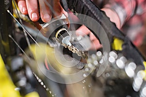 Close-up of a man`s hand, led by masters, lubricate the bicycle chain of a mountain bike with a special lubricant in the