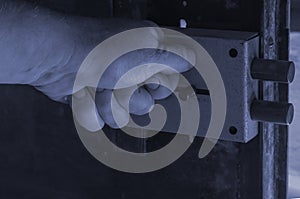 Close-up of a man`s hand locking a massive door lock on a metal door