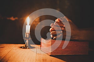 Close up man`s hand is praying in the Church with lit candle