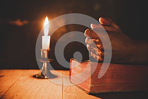 Close up man`s hand is praying in the Church with lit candle,