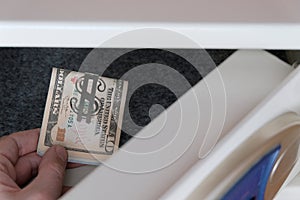 Close-up of a man`s hand puts a pack of USA money stapled with a dollar sign in the safe. Protection of money and precious things