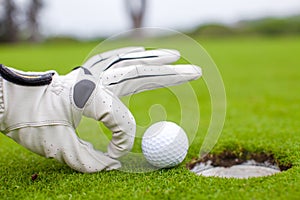 Close-up of a man's hand putting golf ball in hole