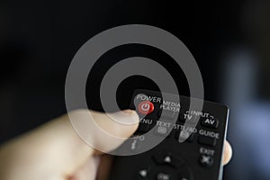 Close up on a man`s hand with the remote control want switch on the TV and presses the button on the remote control