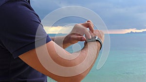 Close-up of a man `s hand with smart watch, uses a smart watch on the sea background