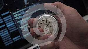 Close-up of man`s hand starting up a stopwatch at hacker programmer screen background. Deadline concept. 4K, 10 BIT, 4:2