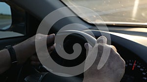 Close-up of a man`s hand on the steering wheel while driving a car. Man driving a car