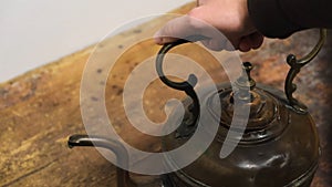 Close-up of man`s hand taking an old iron kettle from the wooden board. Concept. Exposition at the Museum photo