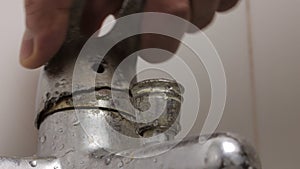 Close-up of a man's hand turning the broken lever of a water faucet