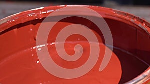 Close-up of a man`s hand wetting a brush in a jar with paint