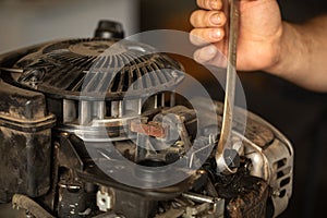 Close-up of a man& x27;s hand with a wrench. The process of repairing an old gasoline engine of a lawn mower.