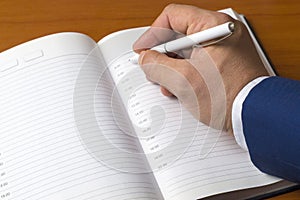 Close-up of a man`s hand writes in a diary. Businessman plans a working day. Time management, action plan