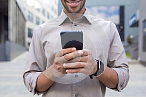 Close up of man's hands, businessman in shirt holding phone, using app on smartphone, walking in city outside office
