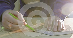 Close-up of a man`s hands draw a piece of furniture on a board.