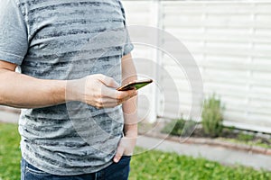 Close-up of a man& x27;s hands holding a mobile phone on the street. Online communication, chatting, wireless