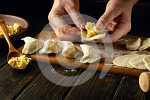 Close-up of a man's hands making a dumpling from dough. The concept of cooking dumplings with potatoes on the kitchen table.