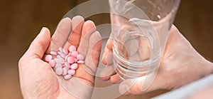 Close-up man`s hands with pills and glass of water