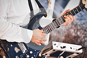Close-up of a man`s hands playing the fretboard of an electric blues guitar