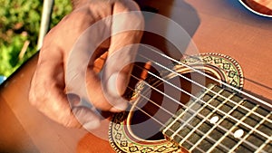 Close-up of a man's hands playing the guitar. The musician plays an acoustic guitar, closeup shot. Male fingers fast