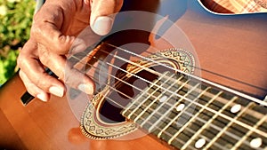 Close-up of a man's hands playing the guitar. The musician plays an acoustic guitar, closeup shot. Male fingers fast