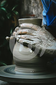 Close-up of a man`s hands shaping clay on a rotary table