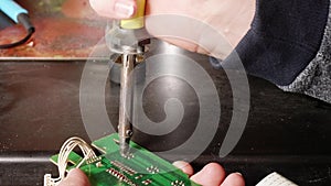 Close up of man`s hands soldering microswitch electrical card using slodering iron.