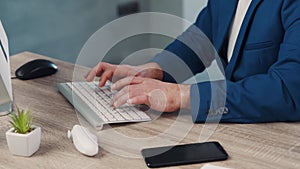 Close-up of man's hands typing on keyboard in office