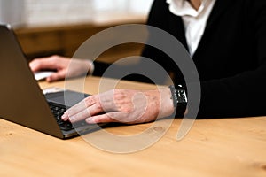 Close-up of a man`s hands typing on a laptop keyboard. Cropped image of a young man working on his laptop in a coffee shop