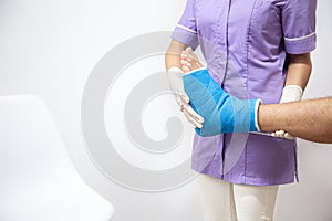 Female doctor in a blue medical gown checking broken leg on male patient