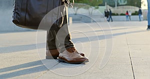 Close up on man's legs wearing brown classic suit and brown shoes on the square