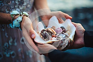 Close up of man`s and woman`s hands holding sea shells