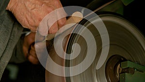 CLOSE UP: Man sandpapering a piece of wood into a knife handle in his workshop. photo