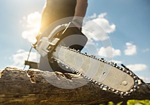 Close-up of a man sawing a log with a chainsaw