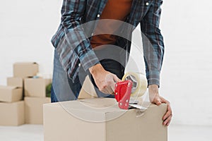 close up man sealing cardboard box with duct tape. High quality beautiful photo concept