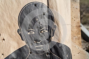 Close up on man shaped range target on the shooting range after the training with bullet holes - crime and terrorism or police