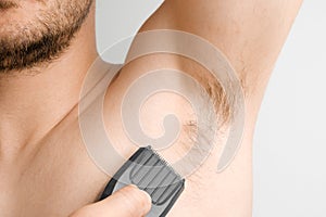 Close up man shaves hairy armpits with an electric razor. Unshaved armpits or underarm. Depilation and hair remove procedure using